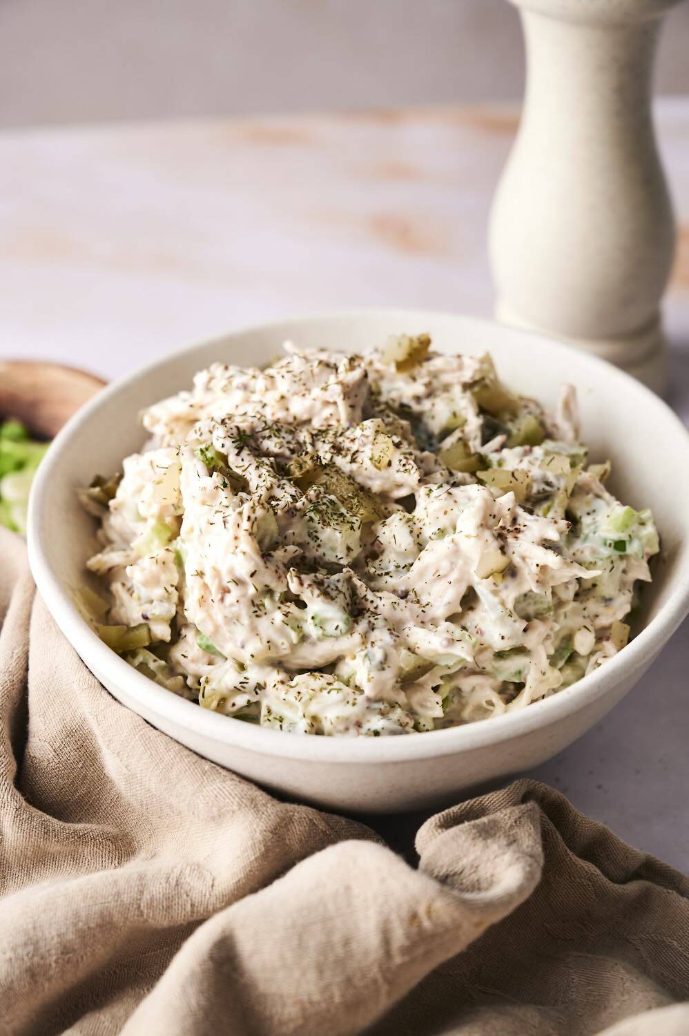 Closeup of a bowl of dill pickle chicken salad in vertical poster style.