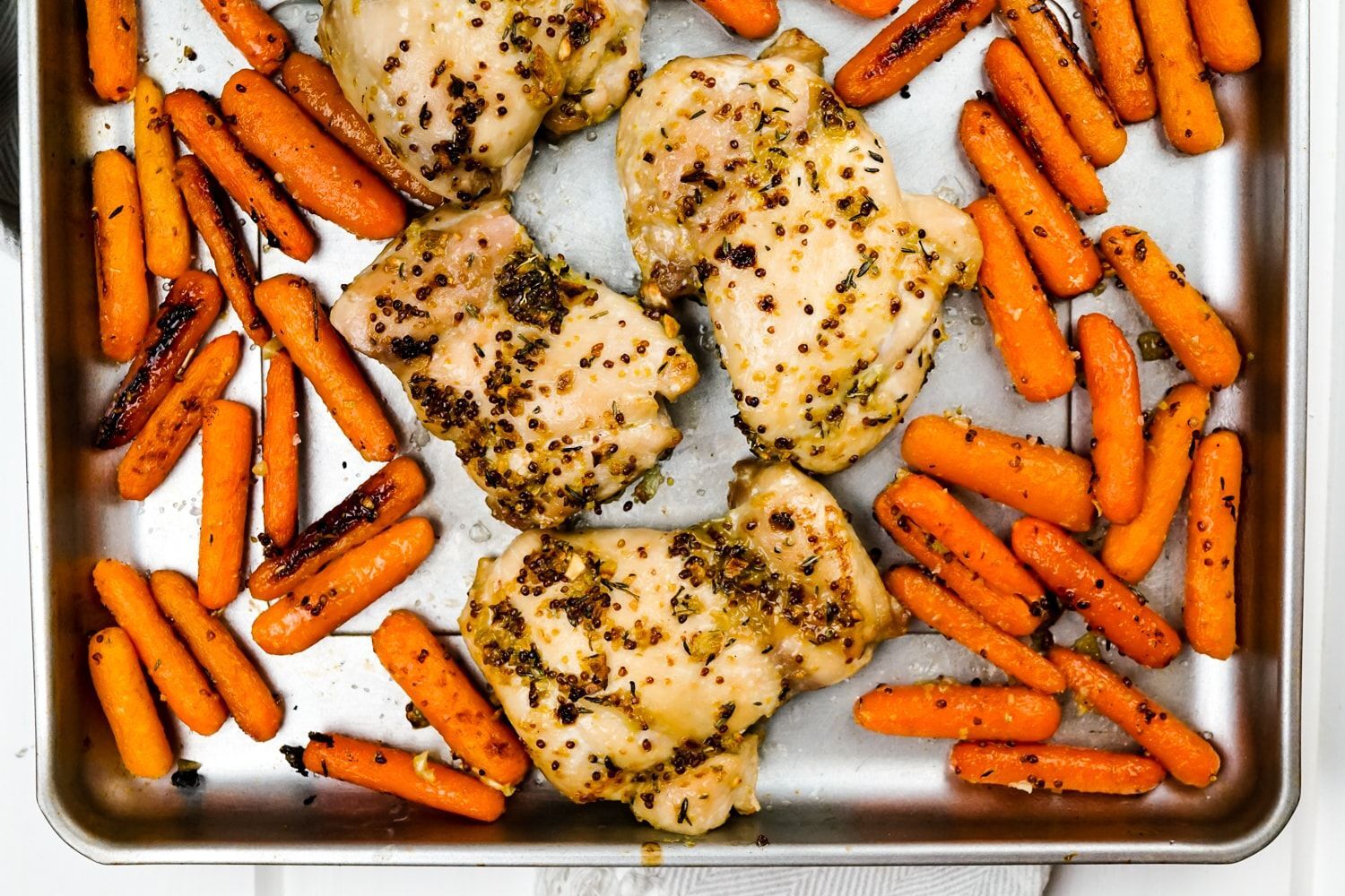 Simple honey mustard chicken thighs are lifted out of the oven in just 25 minutes and surrounded by baby carrots