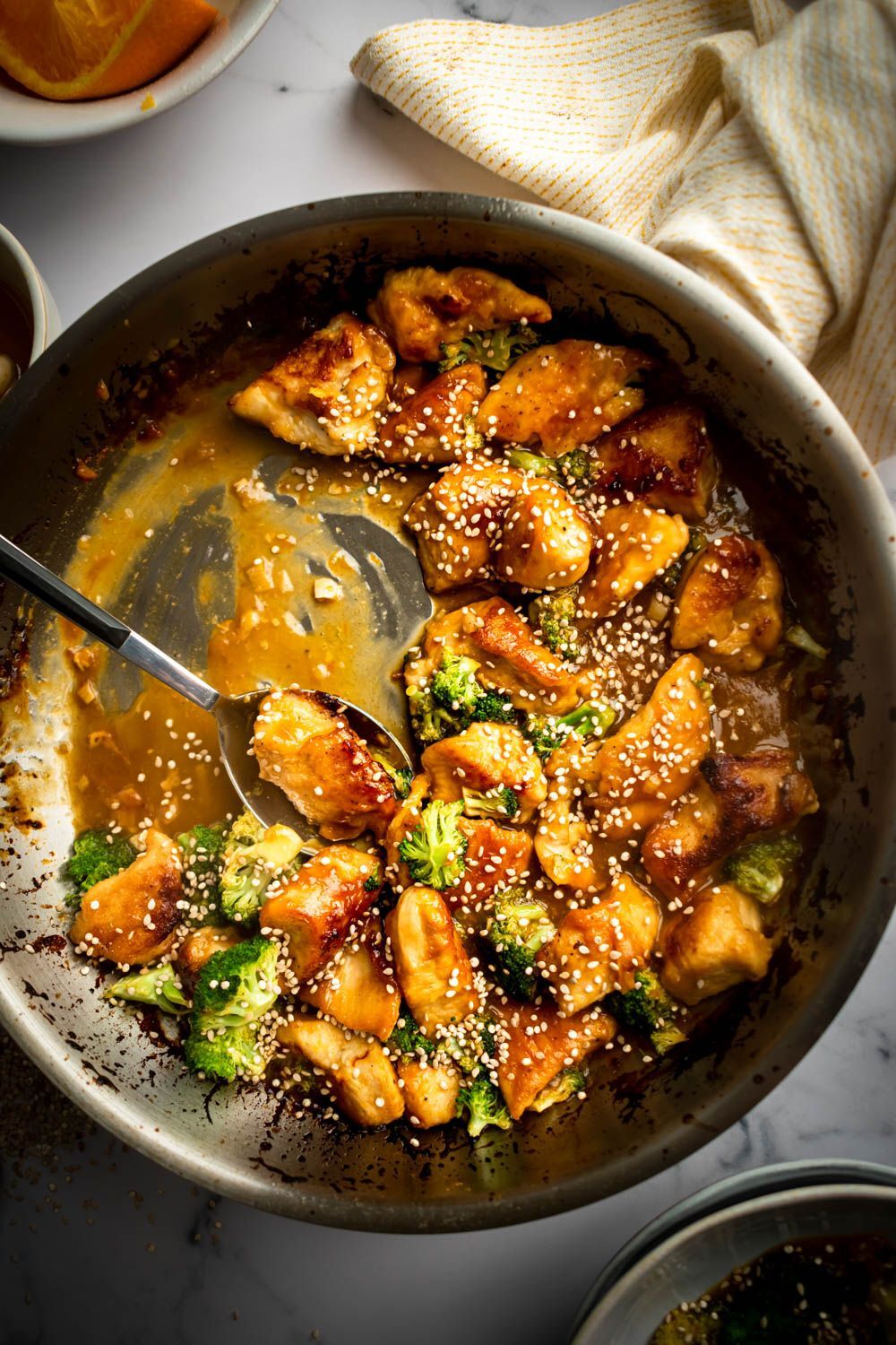 Pan-roasted orange chicken with a thick sauce, broccoli and sesame seeds.