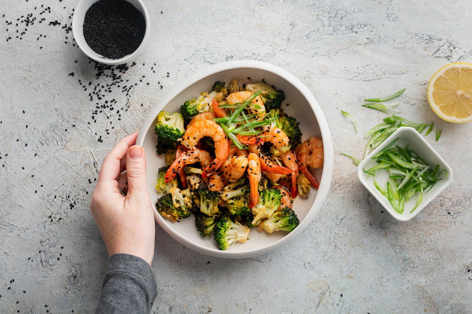 Spicy firecracker shrimp and broccoli flowers in a bowl holding bowl.
