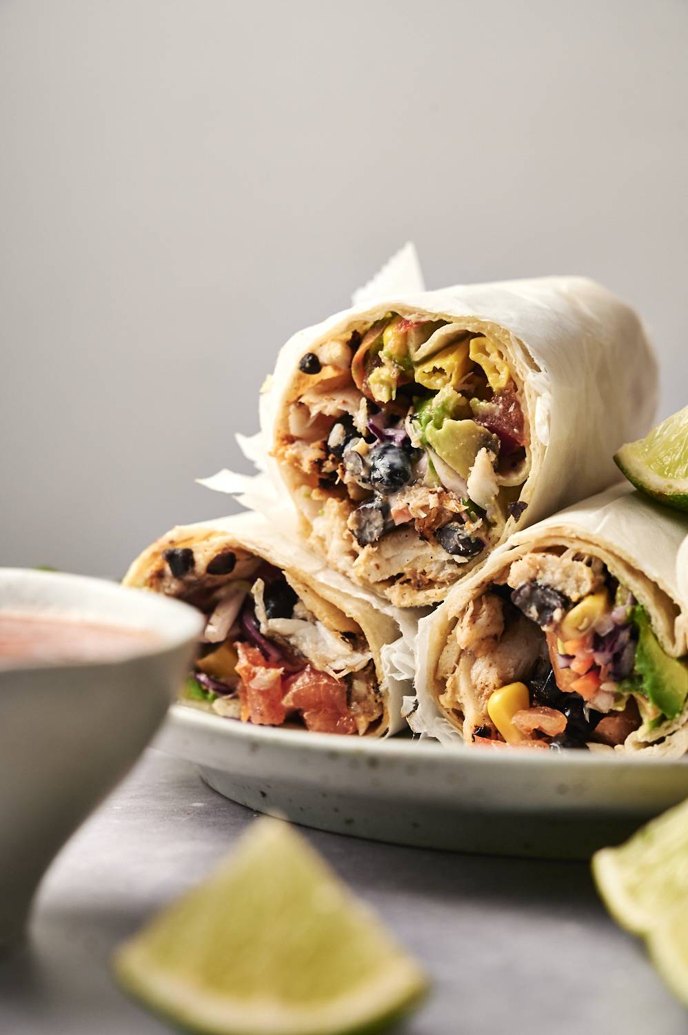Three delicious burritos filled with chicken, black beans and fresh vegetables, served with lemon wedges and dip sauce.