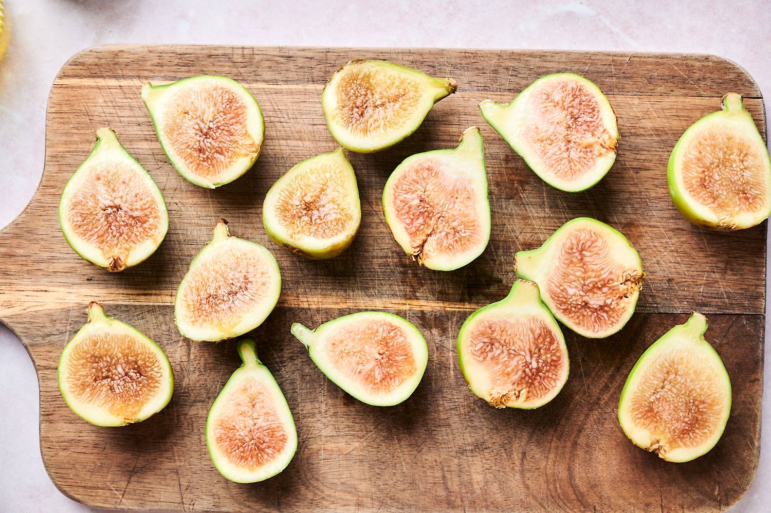 Slice figs on a wooden cutting board for grilling.
