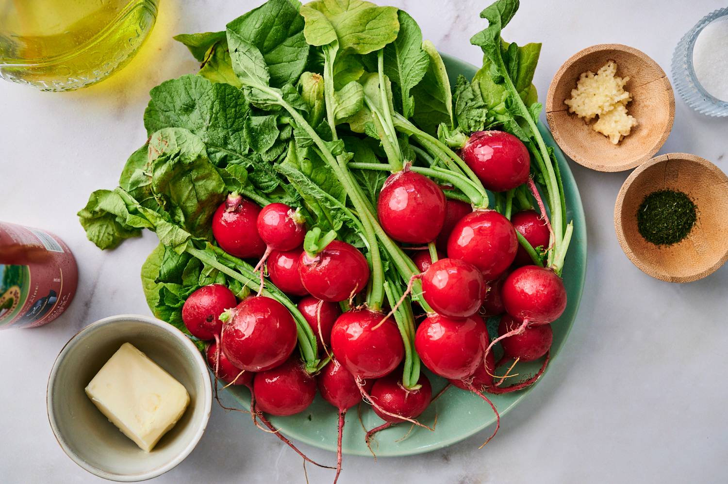Ingredients for grilled radishes including fresh radishes, butter, garlic, salt, pepper, and chives.