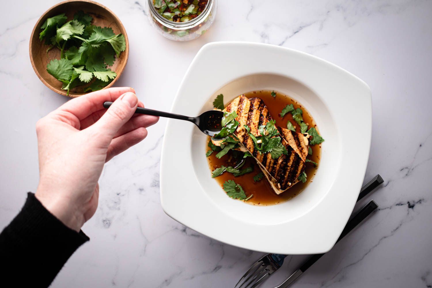 Spoon the fried tofu marinated with cilantro, garlic and soy sauce.