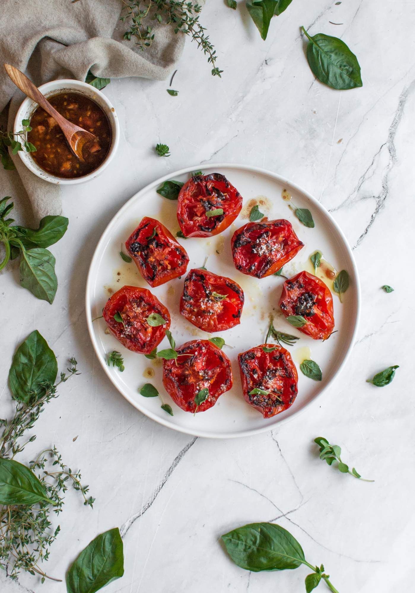 Tomatoes roasted with balsamic vinegar, olive oil, salt, pepper and basil on a plate.
