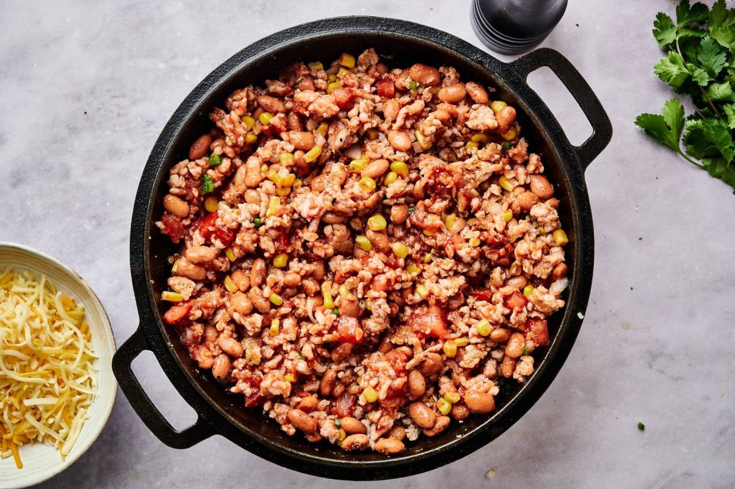 Make taco casserole by adding turkey, pinto beans, corn, tomatoes, and taco seasoning to skillet.