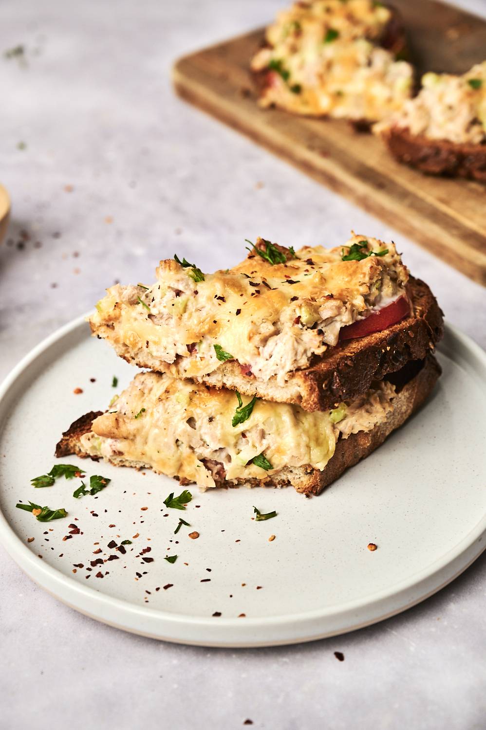 A pile of cheesy roasted tuna melts on the whole grain bread, topped with fresh cilantro and sprinkled with red pepper flakes.