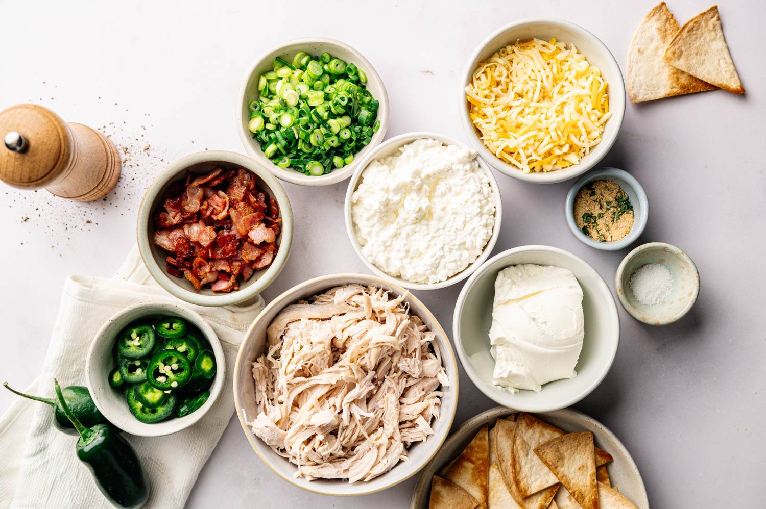 Toppings for the delicious dish include shredded chicken, bacon, scallions, jalapenos, shredded cheese, mozzarella cheese, cream cheese, herbs and salt, with tortilla chips on the side.
