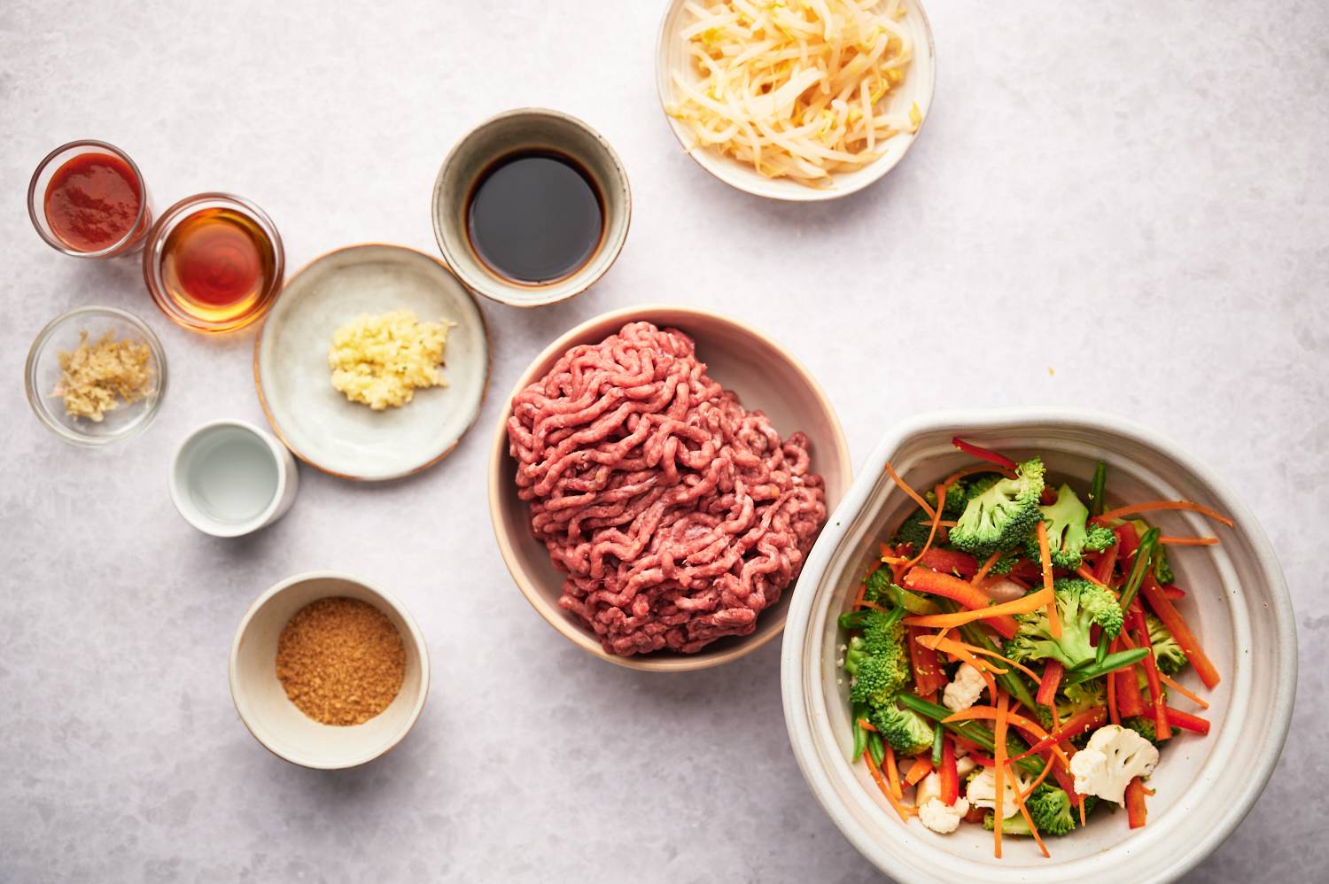 Flat ingredients for a meal: ground meat, fresh vegetables, seasonings and spices, spices in bowls.