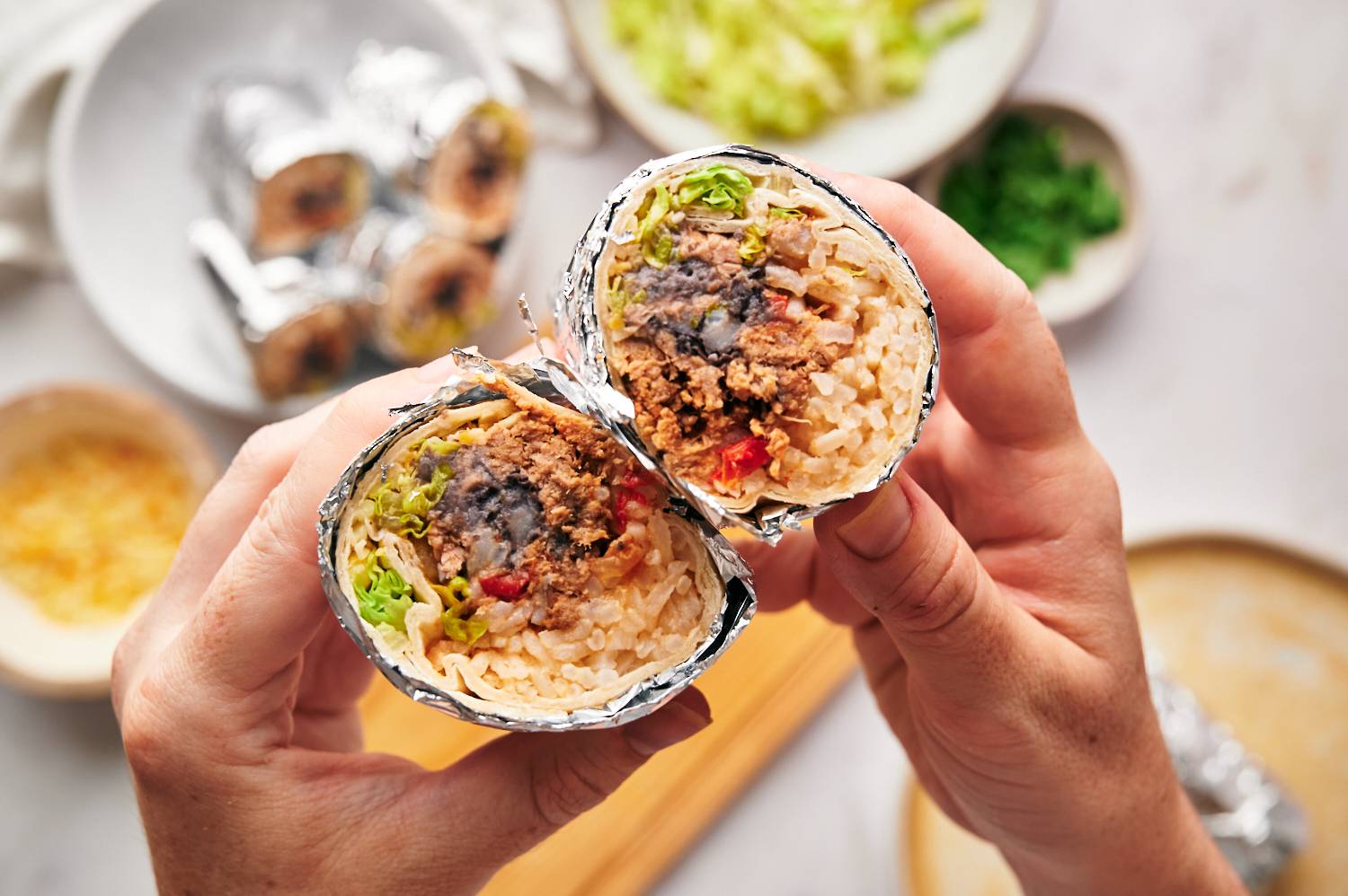 Homemade macaca burritos with beans, rice, cheese, lettuce and salsa rolls in flour tortillas, wrapped in foil.