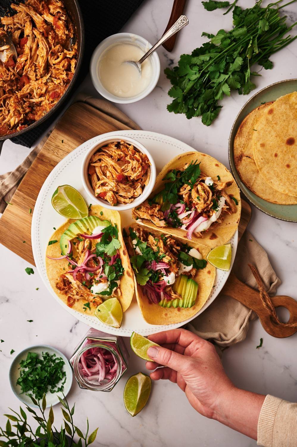 Mexican chopped chicken tacos are served in the tortilla with marinated red onions, avocado, coriander, lime and sour cream.
