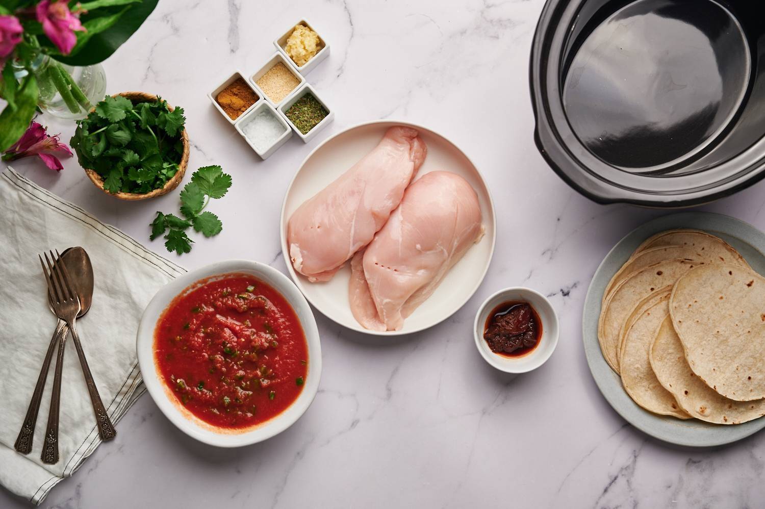 Ingredients for chopped Mexican chicken, including chicken breast, diced tomatoes, spices, coriander, garlic and chili peppers.