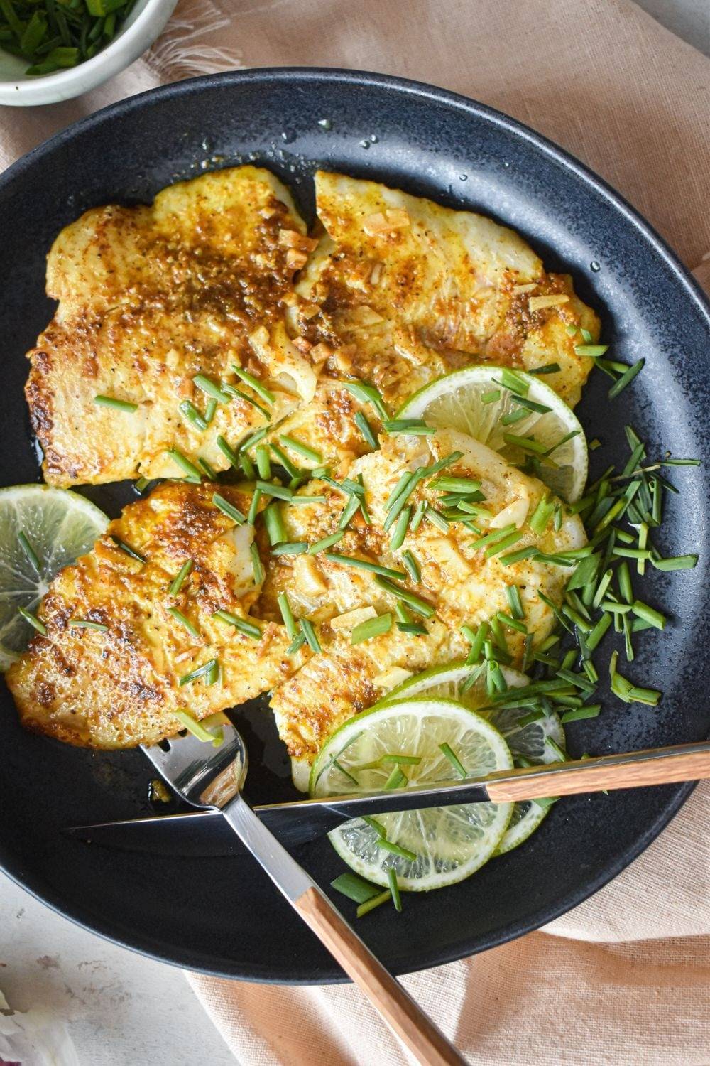 Pan-sear the tilapia with garlic, fresh lime juice, butter and Old Bay seasoning and place on a plate with lime slices and scallions.