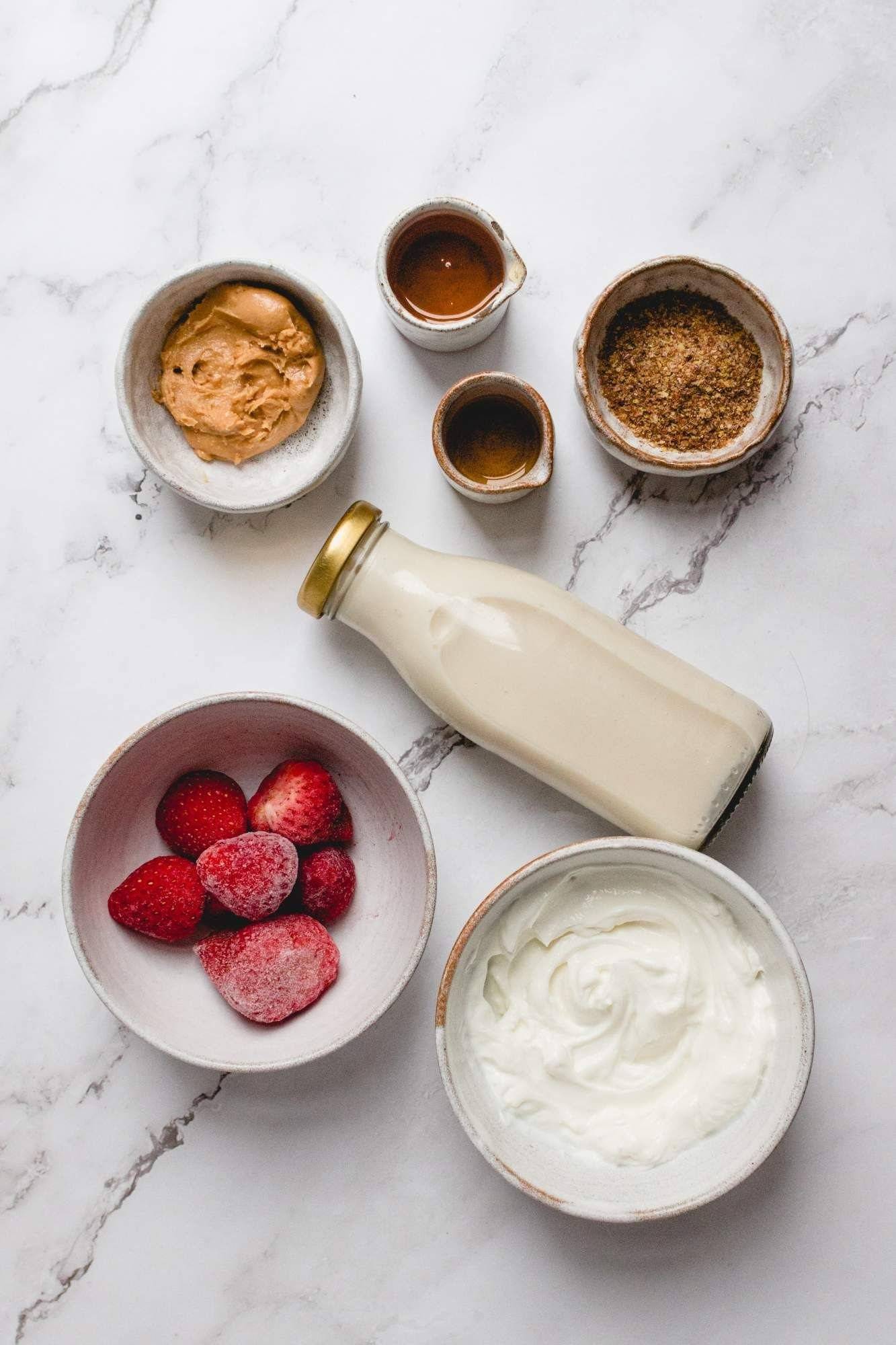 Ingredients for peanut butter and jelly smoothies include strawberries, peanut butter, almond milk, yogurt and flax seeds.