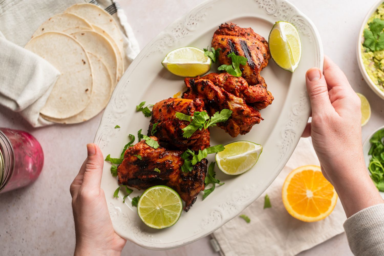 Grilled Pollo Asado sprinkled on a plate with a crimson pickle with lime, cilantro, tortillas and avocado sauce.