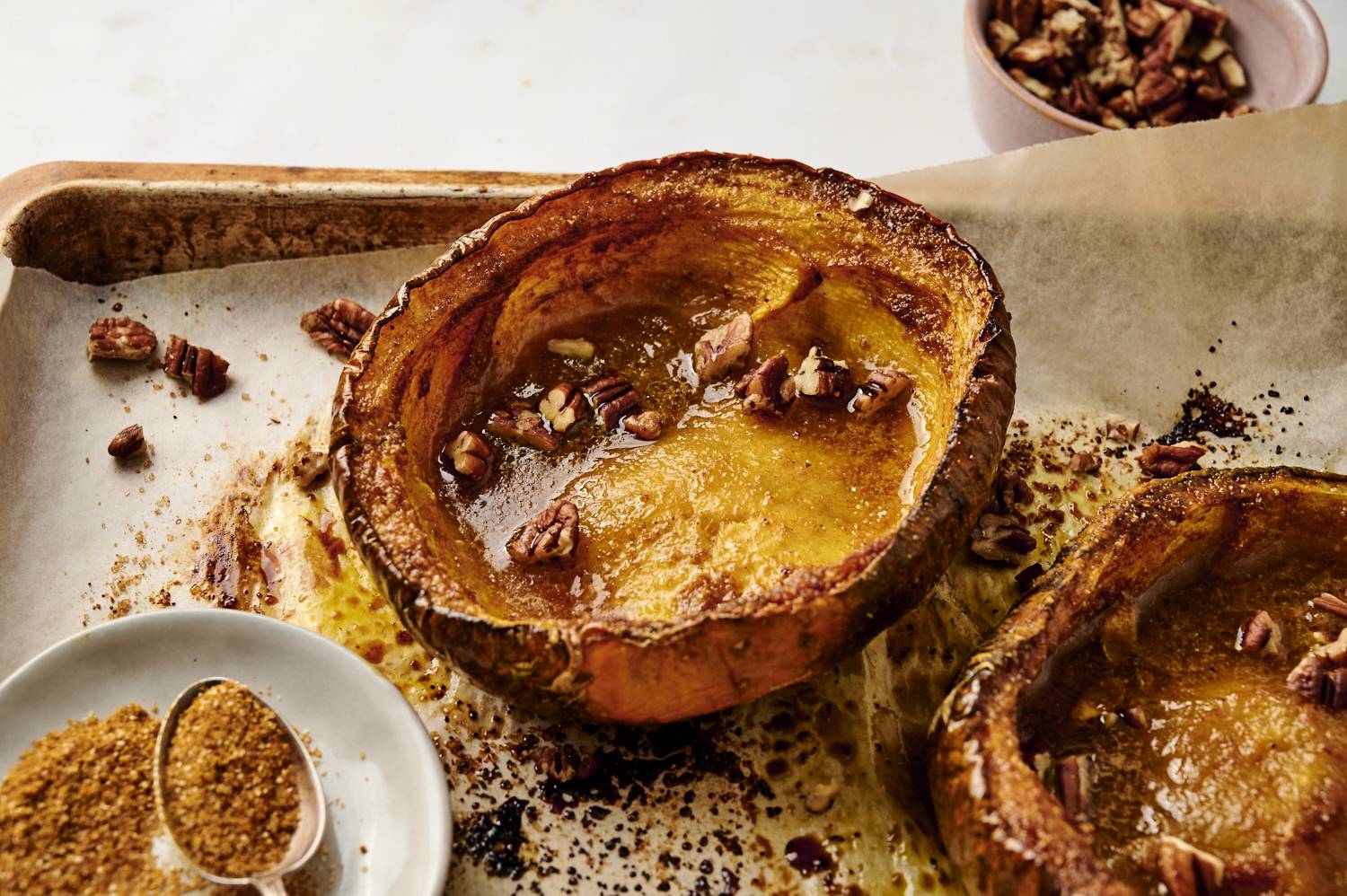 Cinnamon brown sugar roasted acorn squash with walnuts on a baking sheet.