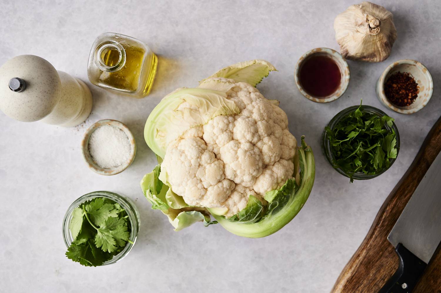 The entire head of the cauliflower is surrounded by fresh herbs, garlic, olive oil, salt and seasonings.