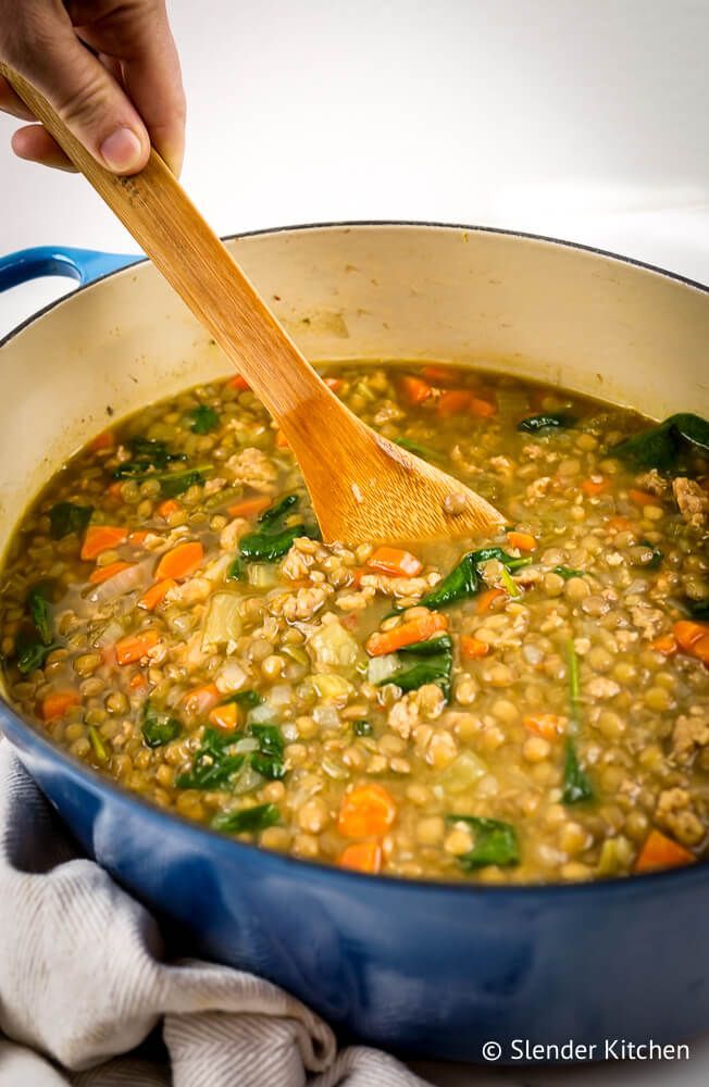 Lentil sausage soup with lentils, sausage, carrots, celery, onion and garlic, stir with hands.