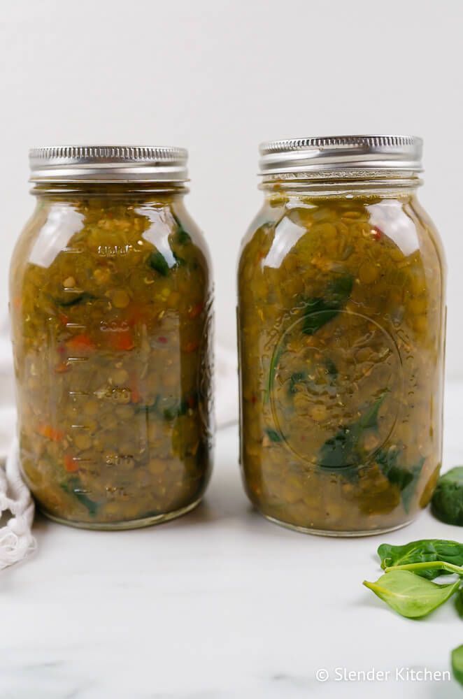 Sausage and lentil soup with two glass mason jars, and some fresh spinach.