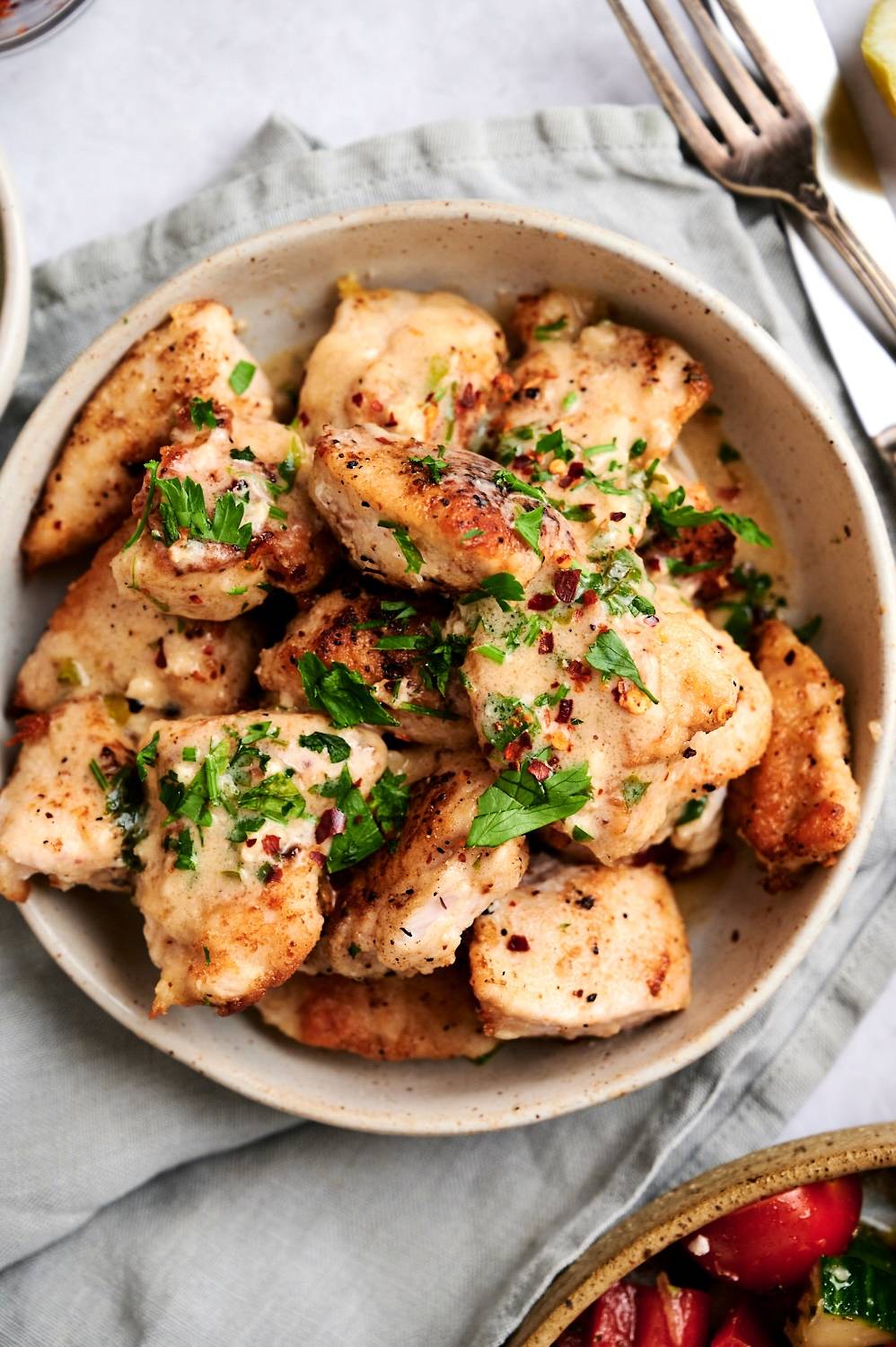 Creamy sauteed chicken breast in lemon pepper sauce served in a bowl with parsley.