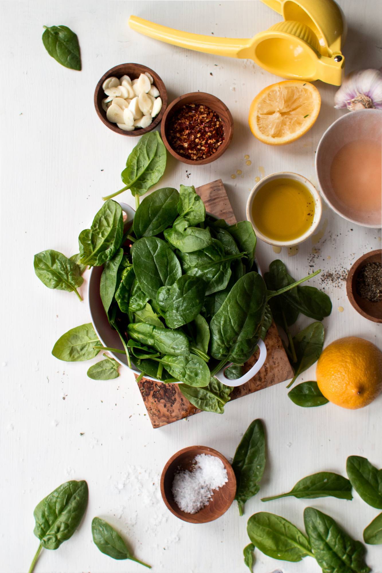 Ingredients for stir-fry spinach, including fresh spinach, lemon juice, olive oil, garlic and red pepper flakes.