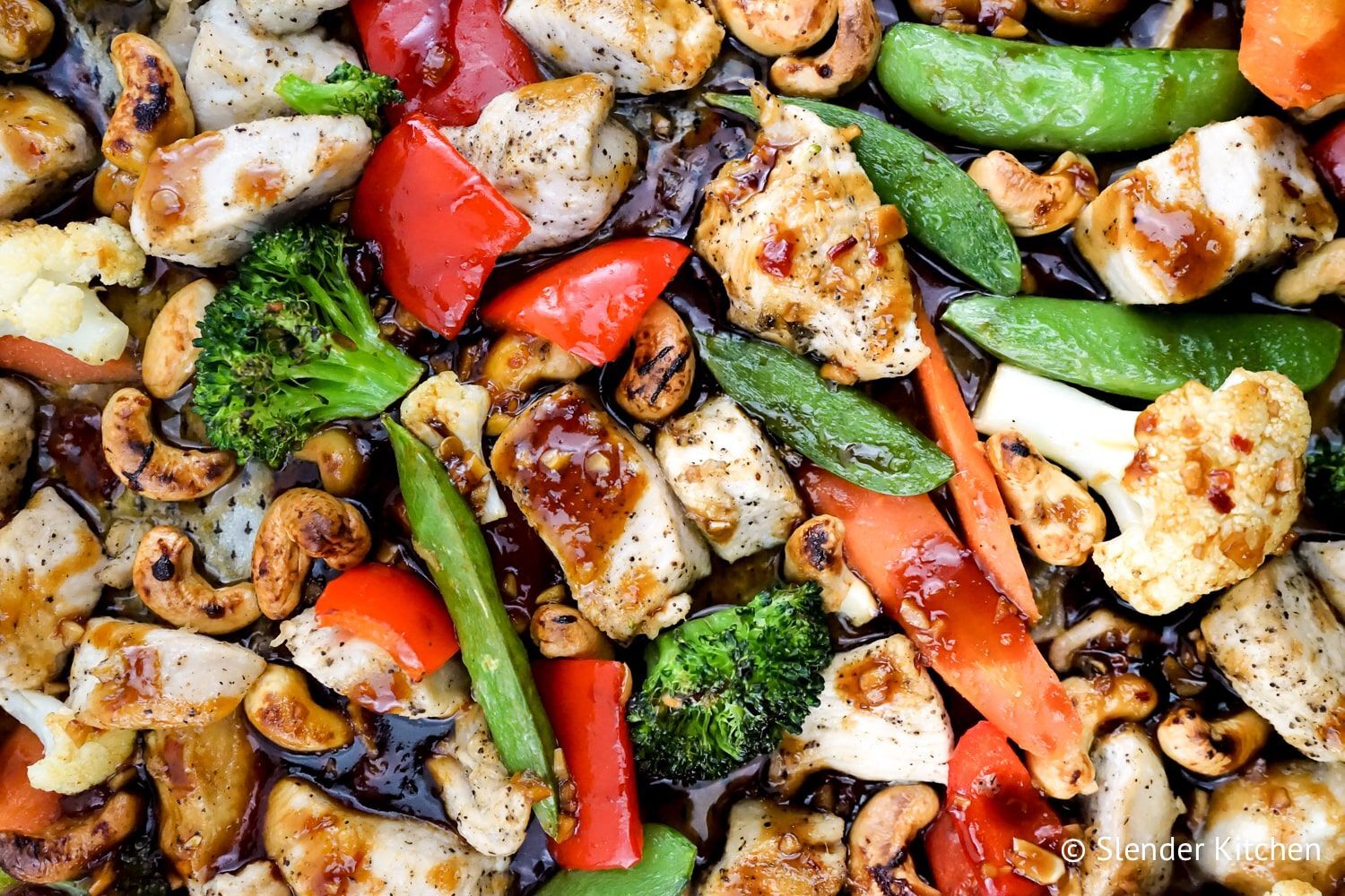 Thai cashew chicken and vegetables served on a sheet pan with a sticky sweet and spicy sauce.