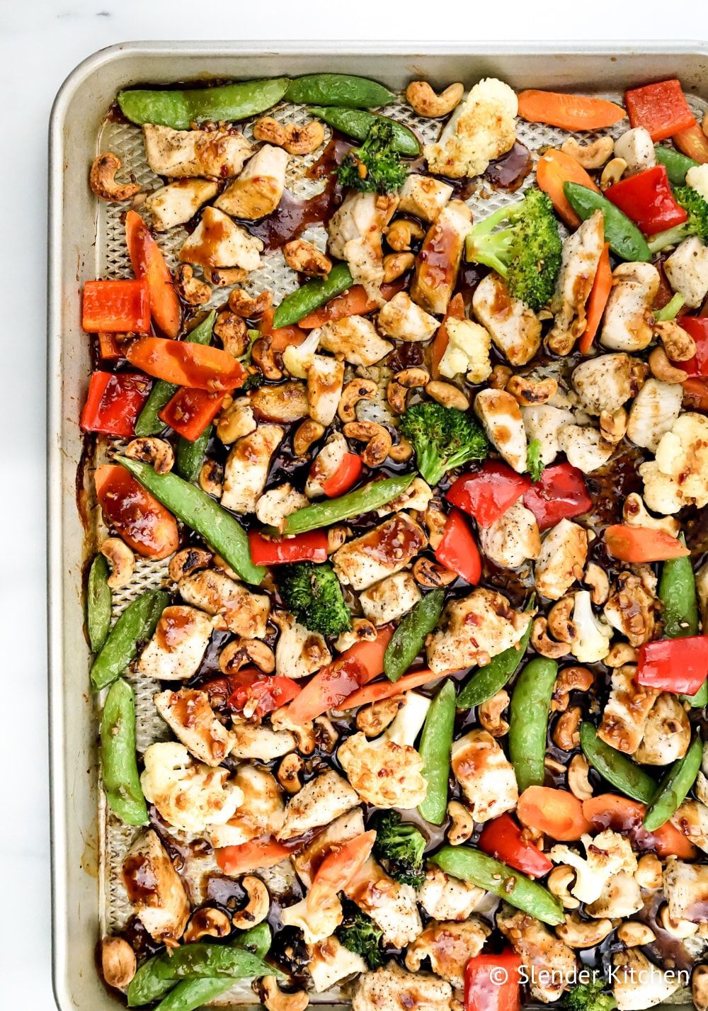 Cashew chicken with vegetables prepared on a sheet pan.