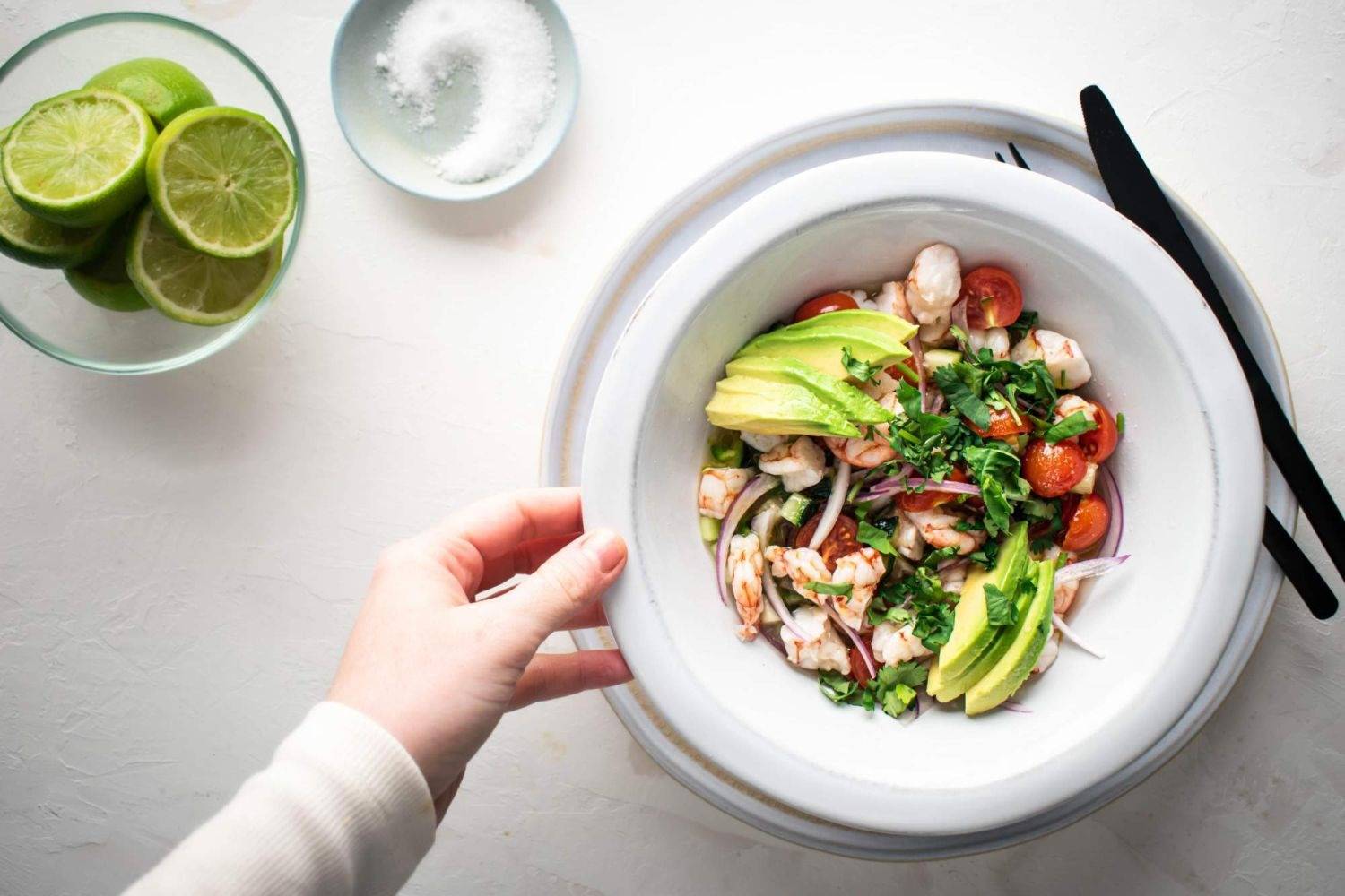 Sprinkle the lime shrimp ceviche with thinly sliced avocado and cilantro, with lime on the sides.