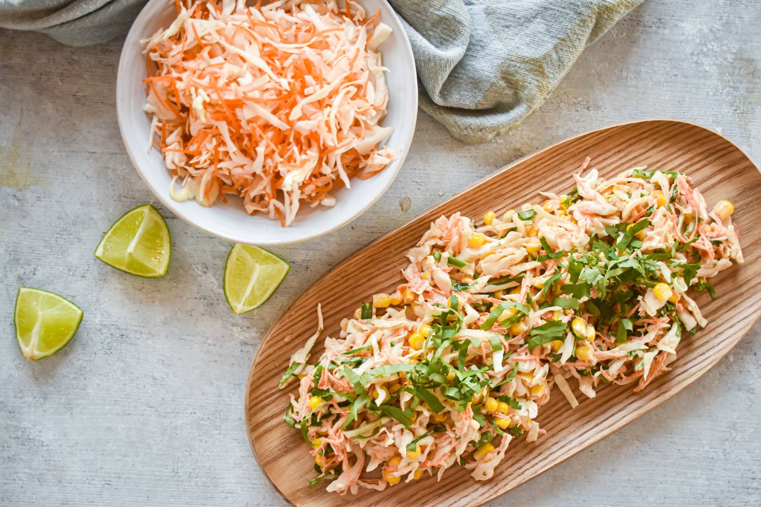Ingredients for cabbage corn slaw including shredded cabbage, carrots, jalapenos, limes, cilantro, and yogurt.