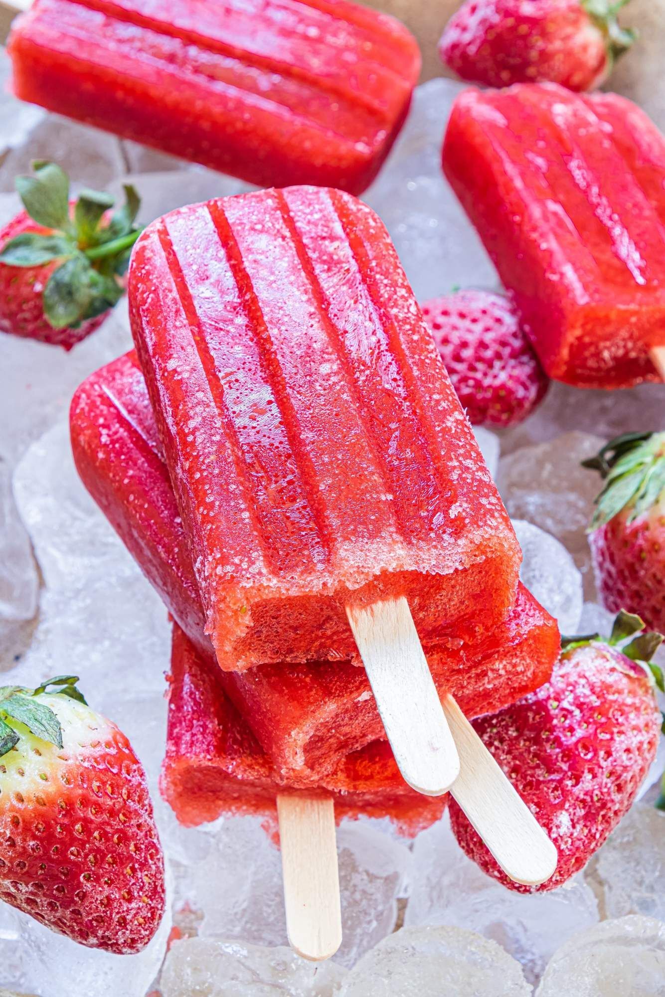 Homemade popsicles with strawberries, honey and water, with strawberries on the side.