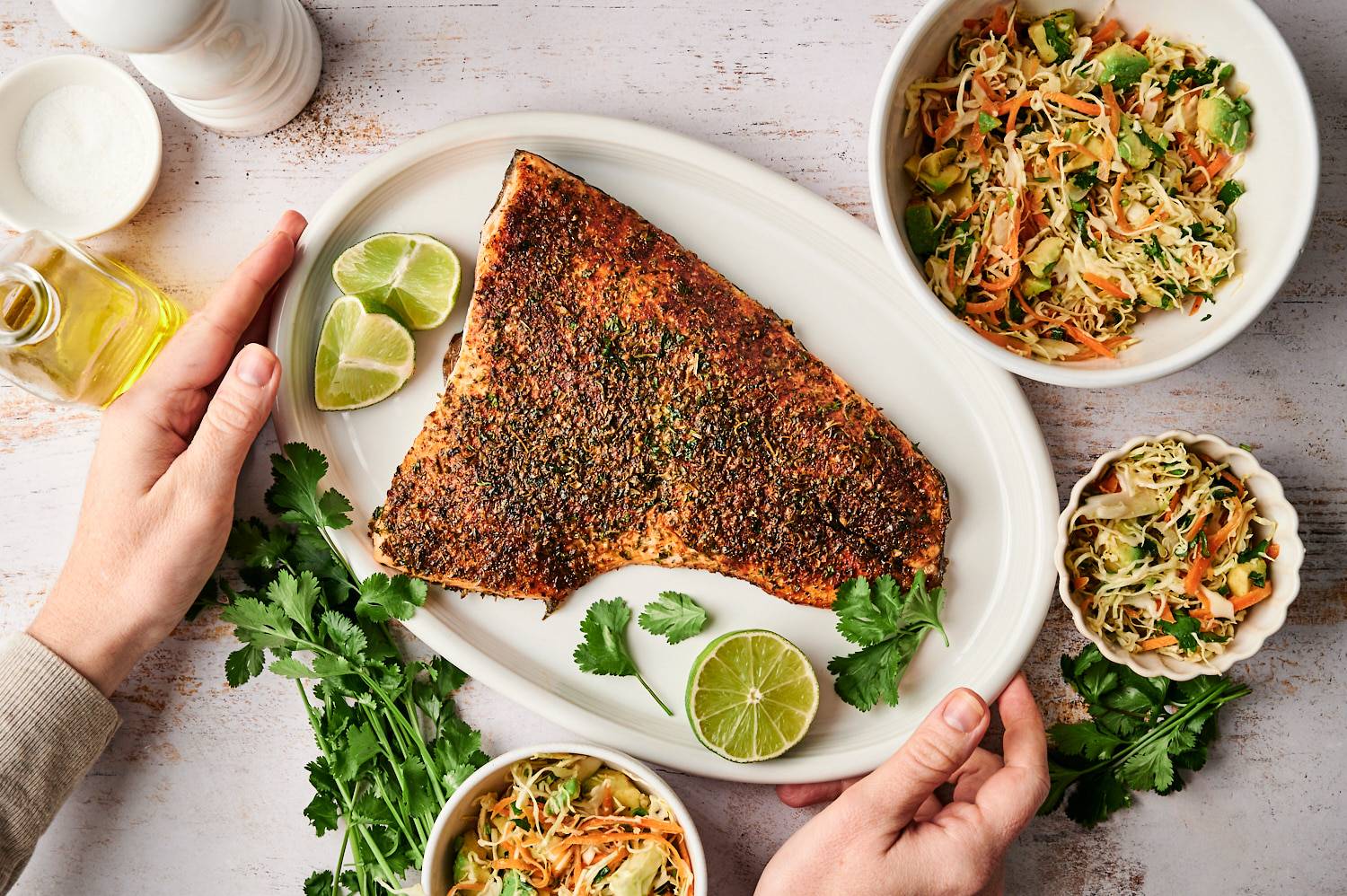 Taco spiced salmon on a plate with avocado cilantro slaw on the side in three bowls.