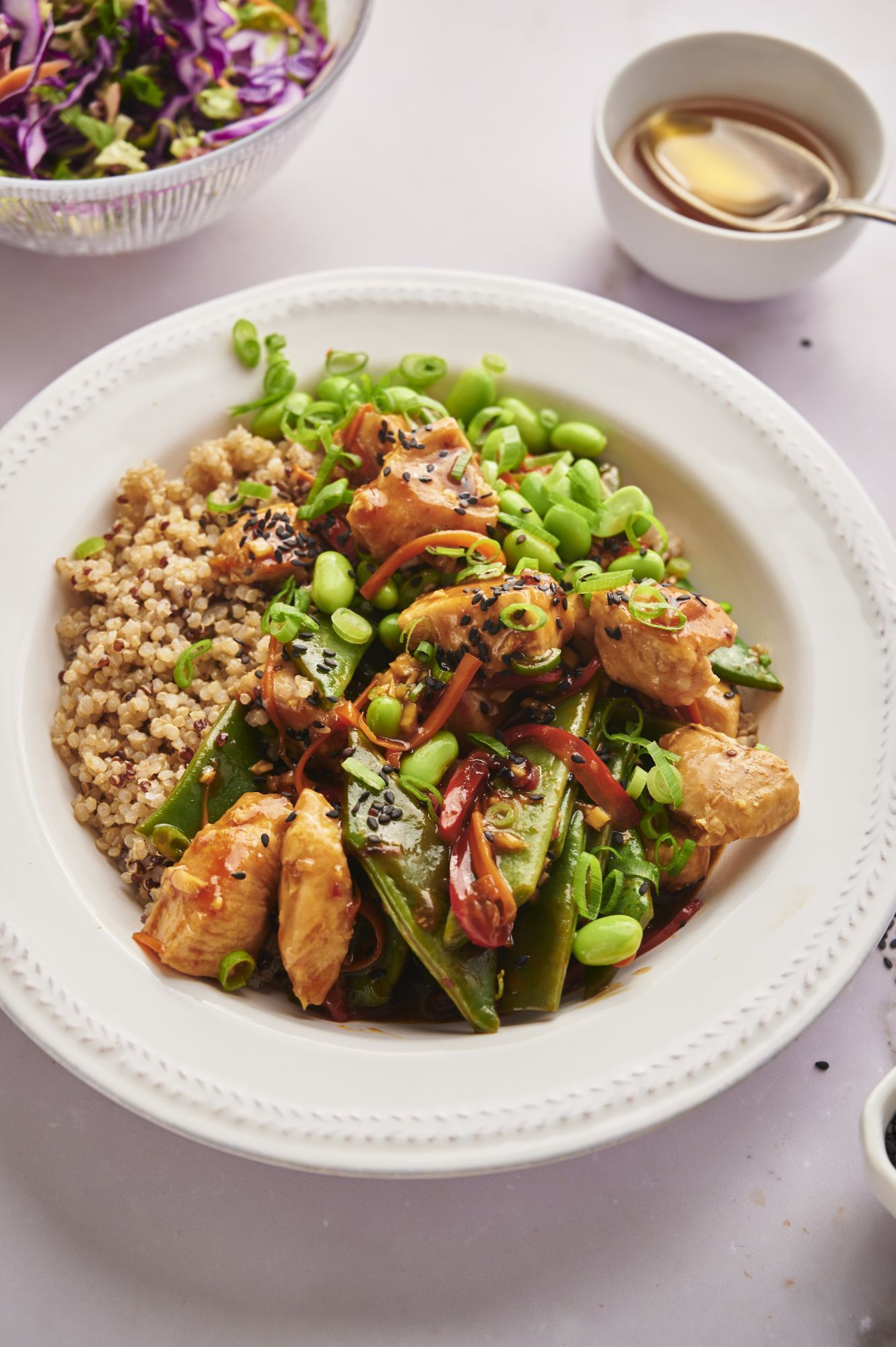Chicken teriyaki bowl with quinoa, chicken breast, vegetables, teriyaki sauce, green onions, and sesame seeds.