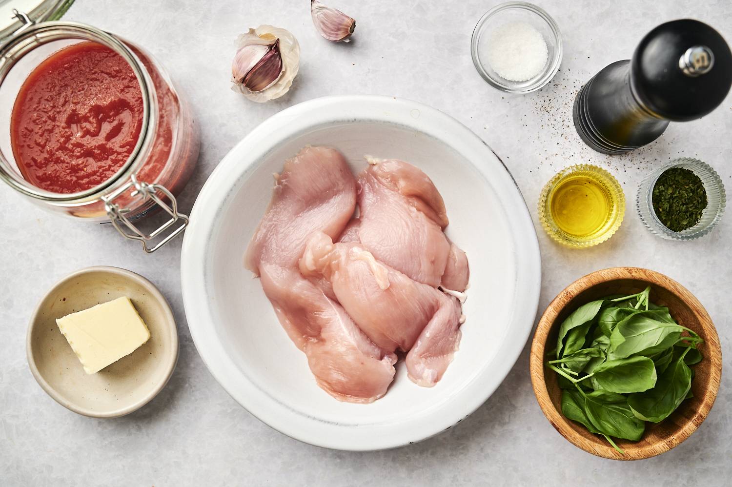 Ingredients for tomato basil chicken including chicken breast, tomatoes, butter, basil, olive oil, and garlic.
