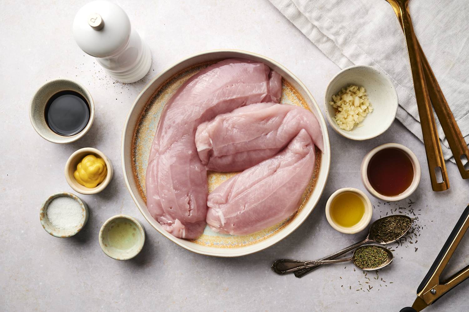 Ingredients for turkey tenderloin marinade including soy sauce, olive oil, mustard, maple syrup, apple cider vinegar, herbs. and garlic.