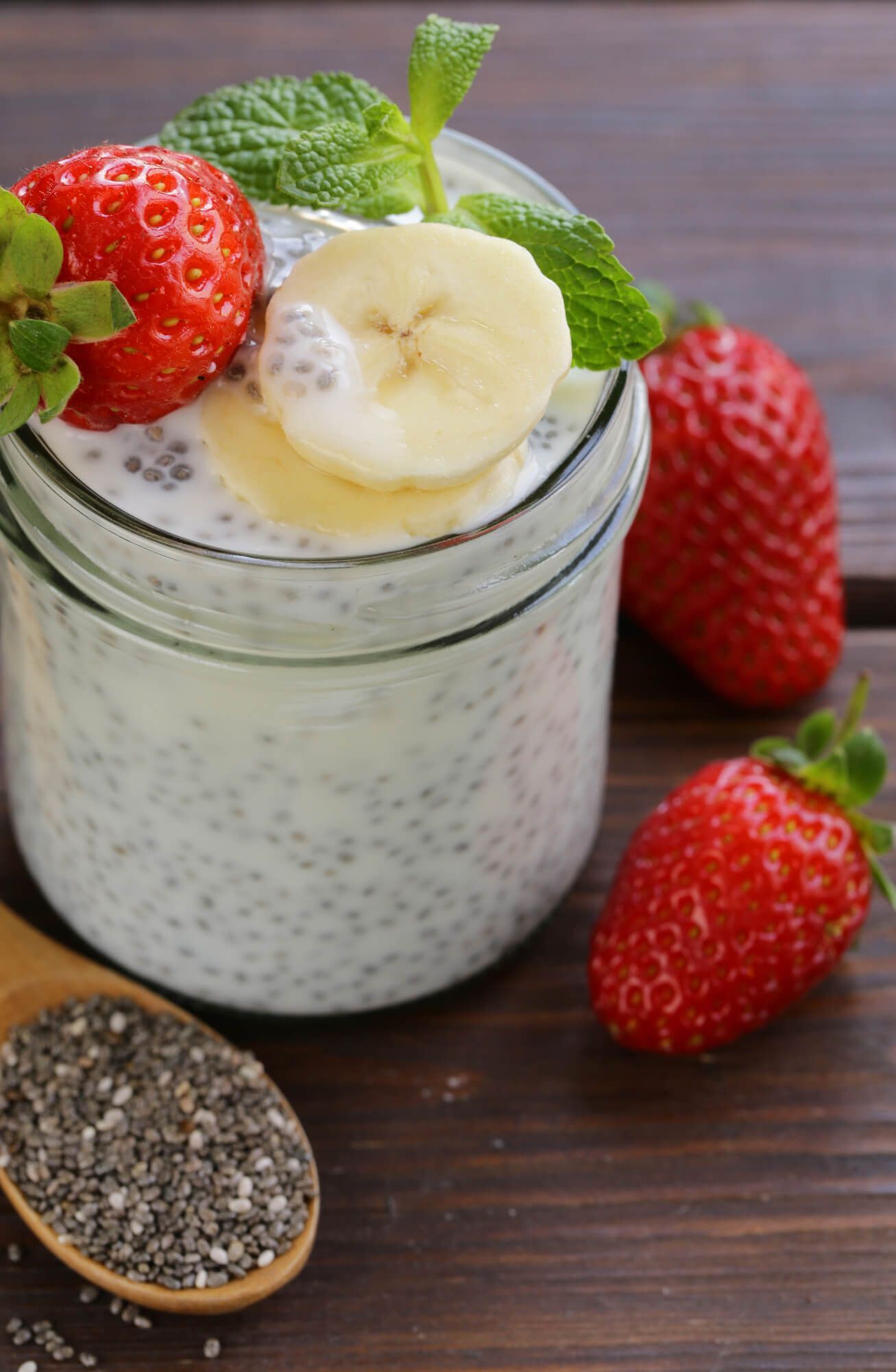 Yogurt chia seed pudding in a glass jar with banana slices and strawberries.