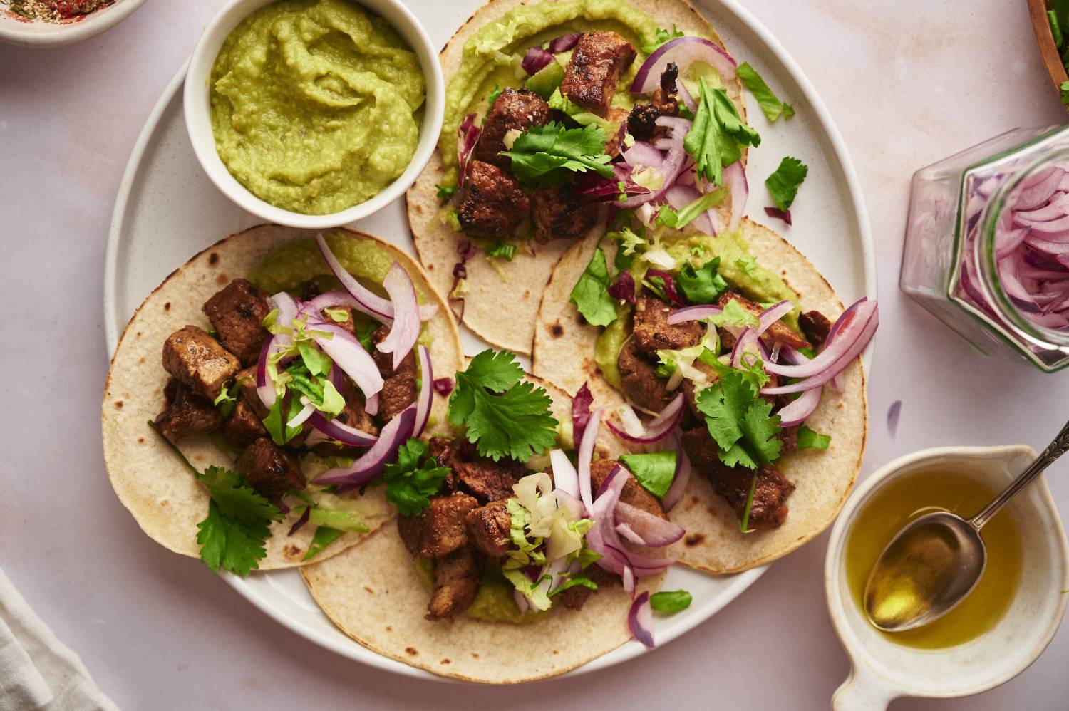 Pork tacos with red onion and guacamole on a plate.