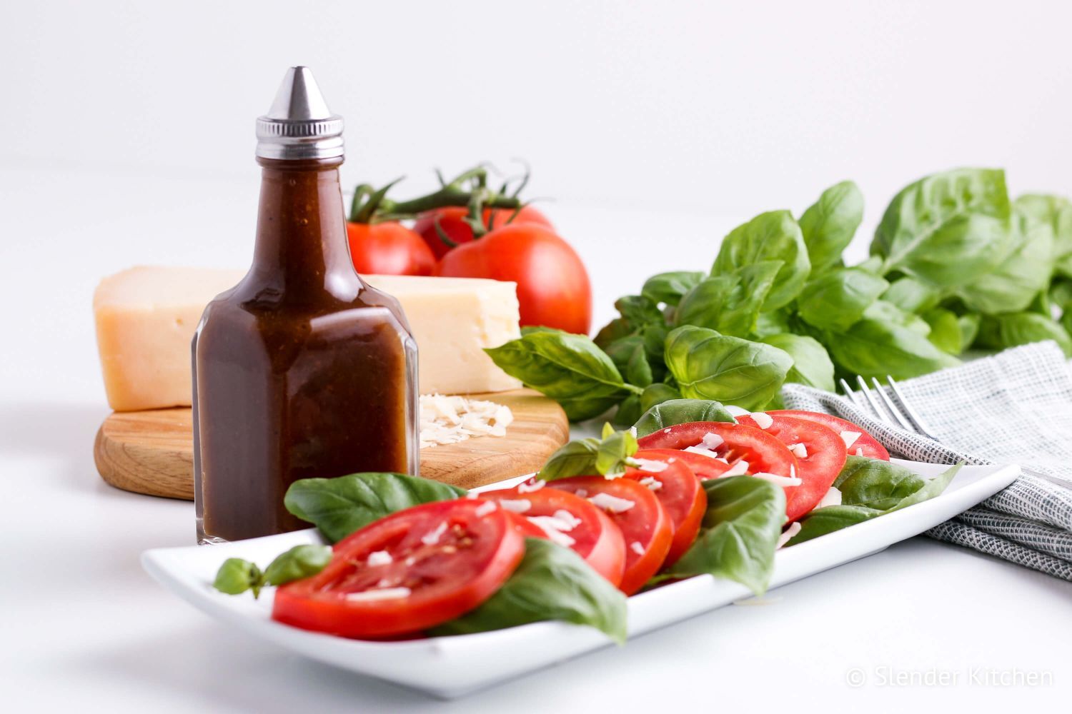 Healthy Balsamic Vinaigrette Balsamic vinaigrette in a glass jar with a tomato and basil salad.