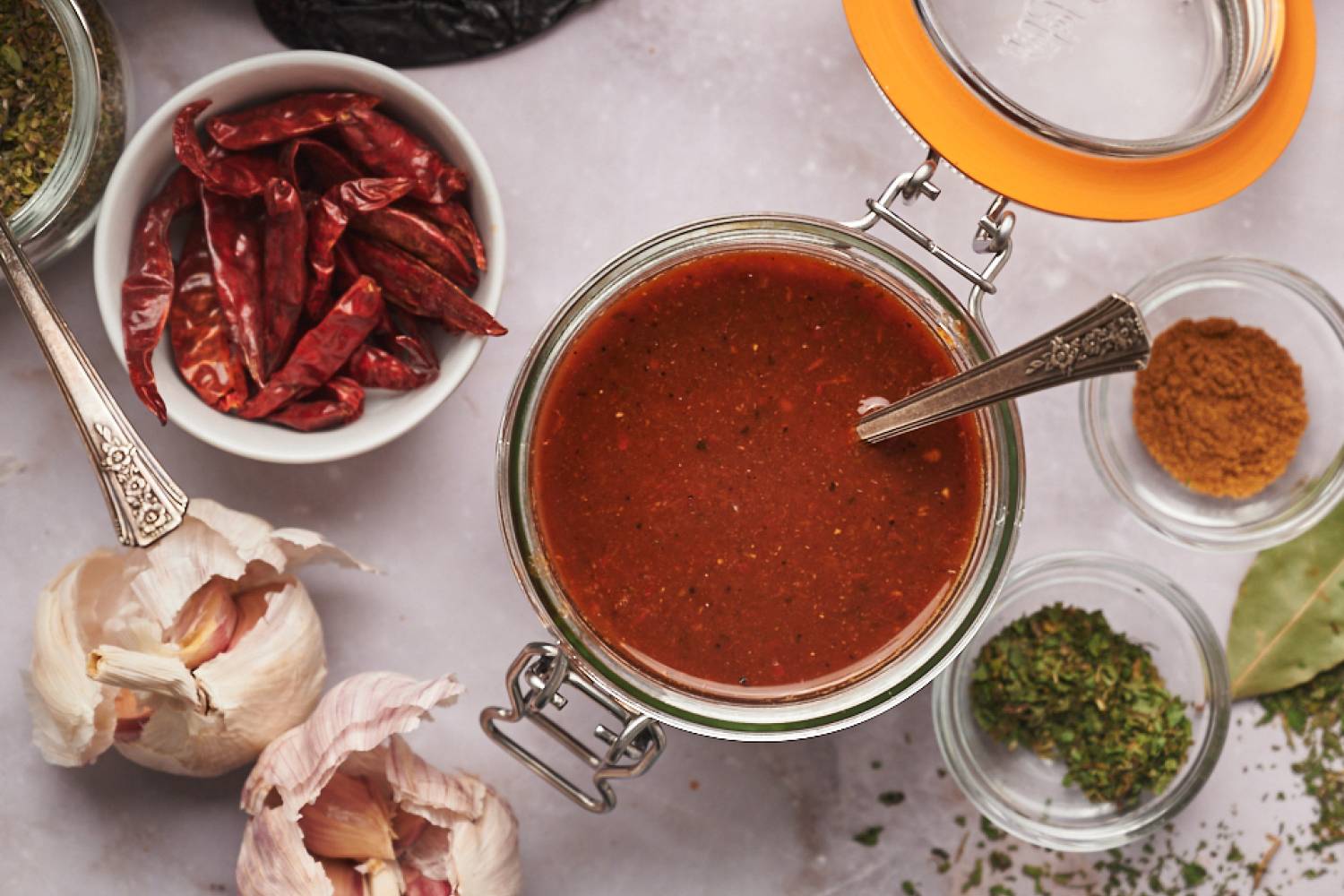 Birria Sauce (Birria Consomé) Birria sauce with dried chile peppers, garlic, onion, tomato, and spices in a glass jar.