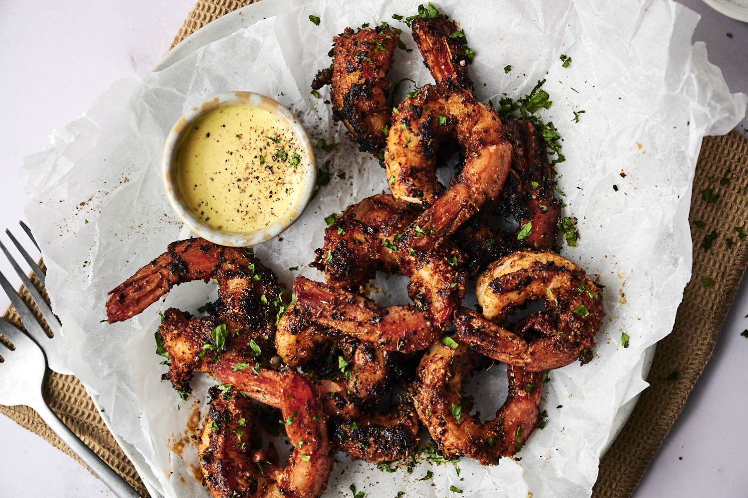 Blackened Shrimp Grilled shrimp garnished with herbs, served with a creamy dipping sauce on parchment paper, ready to enjoy.