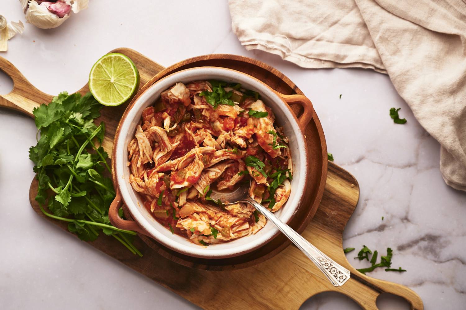 Chicken Tinga Chicken tinga in a bowl with onions, cilantro, avocado, and queso fresco.