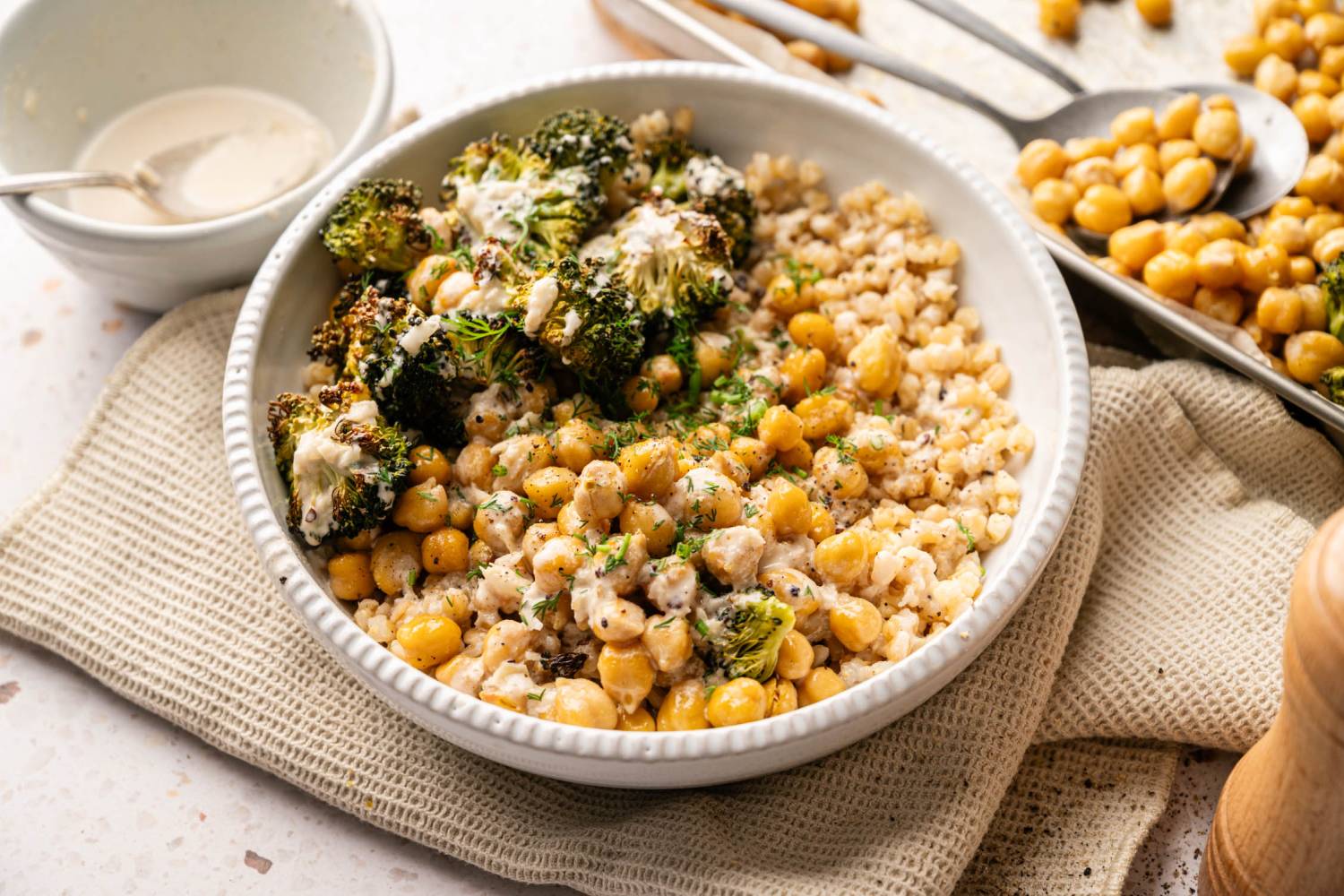 Farro Bowls with Broccoli and Chickpeas A bowl of roasted broccoli, chickpeas, and grains topped with a creamy sauce.
