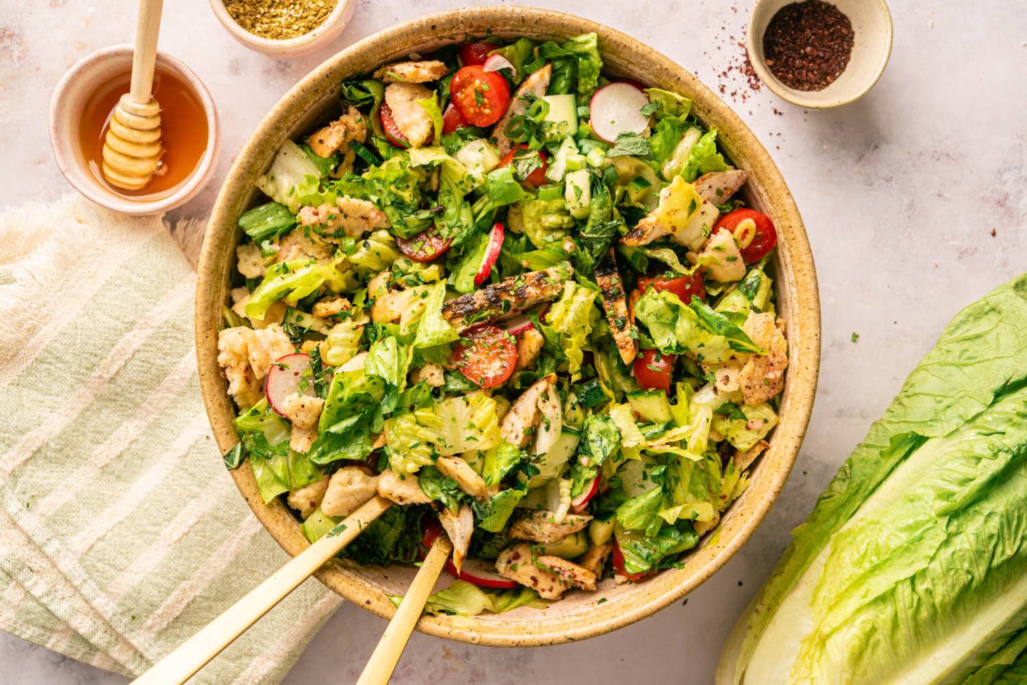 High-Protein Fattoush Salad Recipe Fattoush salad drizzled with dressing, featuring crispy pita, grilled chicken, romaine, and radishes in a speckled ceramic bowl.
