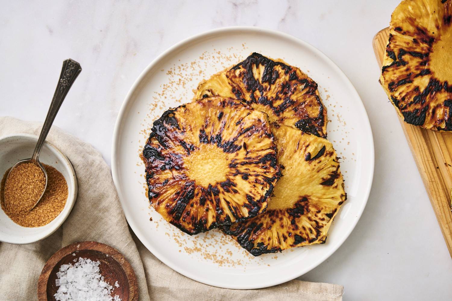 Grilled Pineapple Grilled pineapple with brown sugar and flaky sea salt on a plate.
