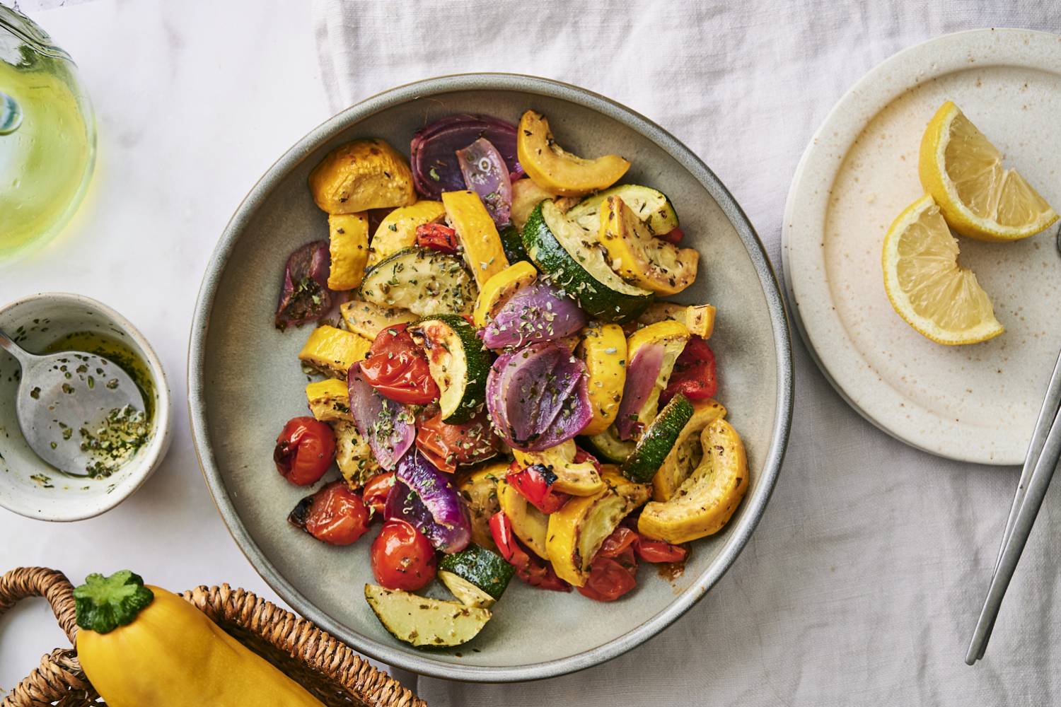 30 Quick and Tasty Grilled Vegetable Side Dishes A colorful medley of roasted zucchini, yellow squash, cherry tomatoes, and red onion served with lemon on a light table setting.