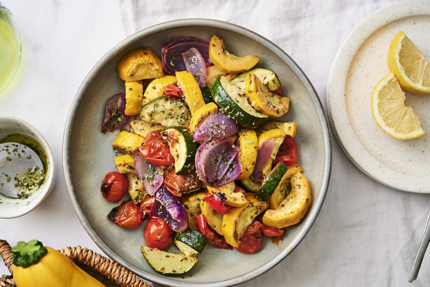 Grilled Summer Vegetables A bowl of colorful roasted vegetables, including zucchini, yellow squash, and cherry tomatoes, garnished with herbs. Lemon slices nearby.