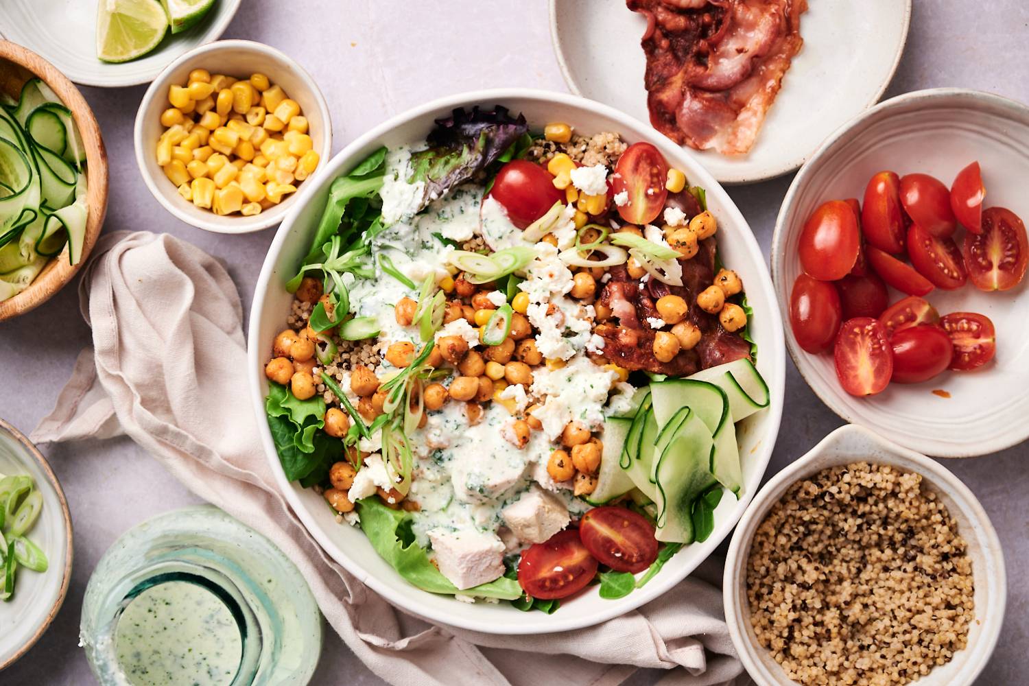 Protein packed salad bowls with chicken, bacon, chickpeas, cucumbers, quinoa, cherry tomatoes, green onions, and cottage cheese dressing.