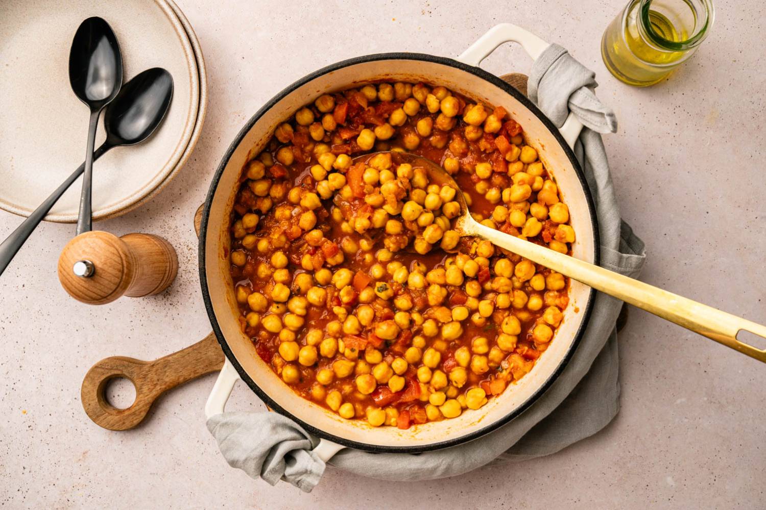 A pot of flavorful chickpea stew with tomatoes and spices sits on a table.