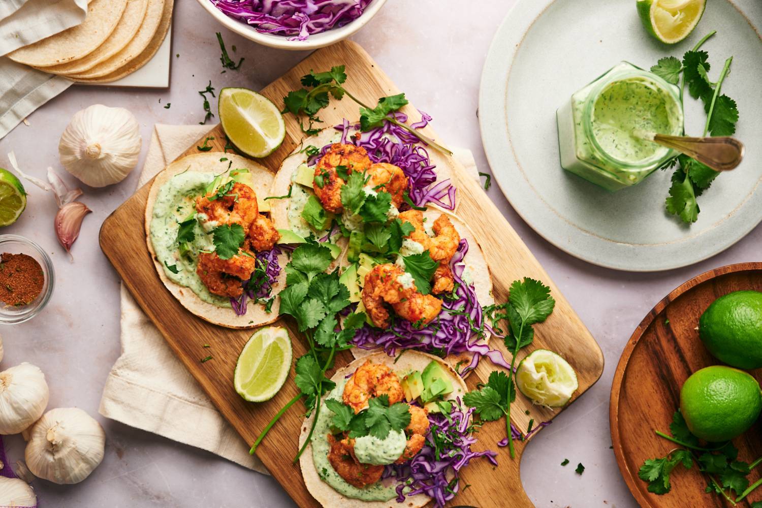Shrimp Tacos Shrimp tacos served on corn tortillas with avocado, cabbage, cilantro, lime wedges, and a creamy sauce.
