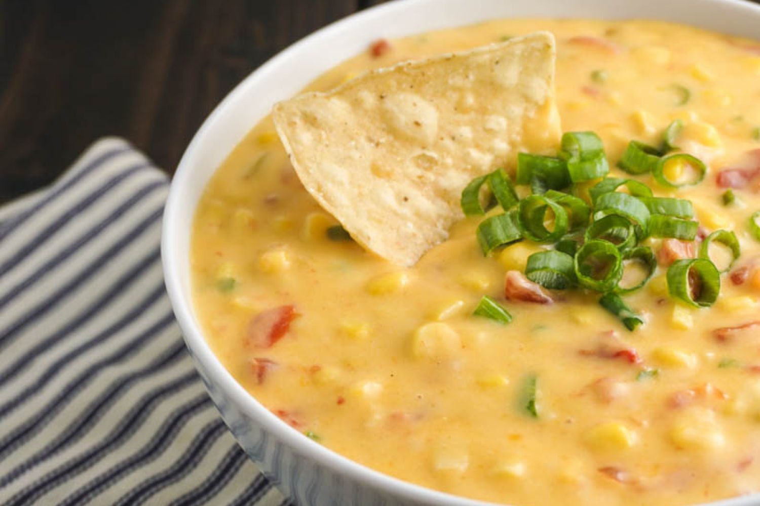Jalapeno Corn Dip Jalapeno corn dip with cheddar cheese, tomatoes, jalapeno, onion, and corn in a bowl.