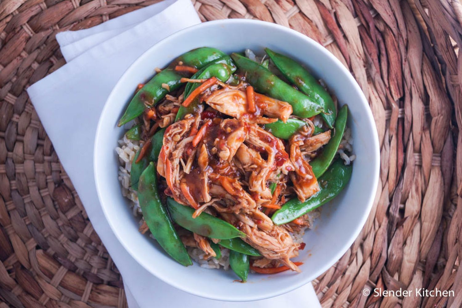 Slow Cooker Spicy Hoisin Chicken Thighs Slow cooker spicy hoisin chicken served in a bowl with carrots and snap peas.